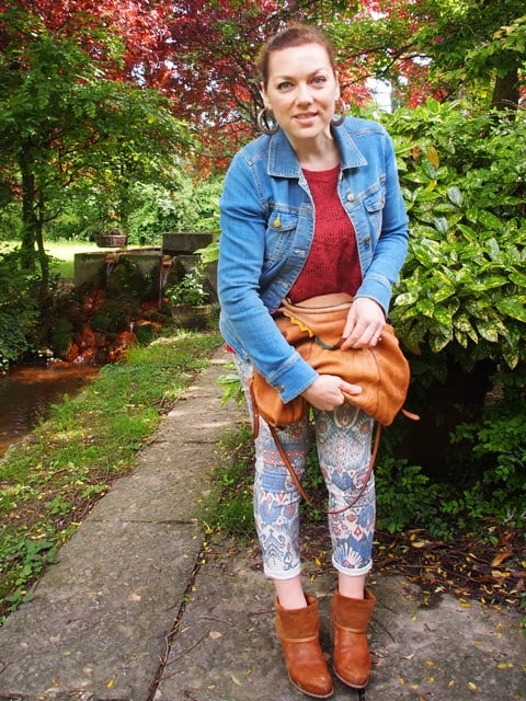 outfit stile tex-mex con giacchina in denim, jeans stampati, stivali e borsa in cuoio